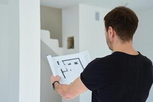 Man analyzing architectural blueprint in apartment photo