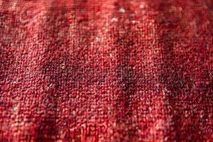 A close-up view of red knitted fabric, showcasing intricate textures and patterns. The macro shot highlights the details of the yarn and weave, creating a cozy and inviting atmosphere. photo
