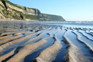 The sandy beach of Etretat, Normandy, France, with the unique cliffs and natural rock formations in the background, creating a scenic and peaceful coastal view photo