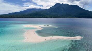 Aerial view of white island sandbar with Camiguin Island in the background. Clear tropical waters and volcanic mountain video