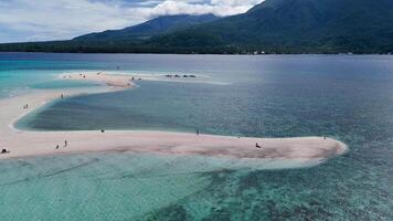 Aerial view of white island sandbar with Camiguin Island in the background. Clear tropical waters and volcanic mountain beautiful video