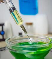 Laboratory studies of biologically active substances. Green chemical liquid in laboratory conditions in a special glass container. A chemical substance is added to the analysis of the reagent with a photo