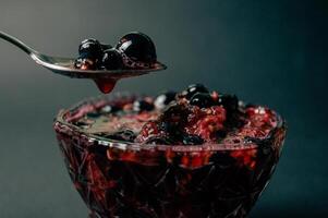 Raspberry and currant jam in a crystal vase on a dark background. Useful treat of dessert with vitamin C. Beautiful photos dessert in a transparent bowl. High quality photo