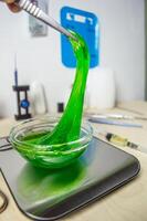 The slime green substance in the laboratory dish is pulled with tweezers. Research and scientific discoveries on the table in the laboratory. High quality photo