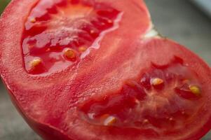 Close photo cut ripe tomato with seeds. Fleshy large tomato with thick partitions grown in the ground . High quality photo