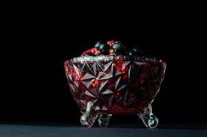 Raspberry and currant jam in a crystal vase on a dark background. Useful treat of dessert with vitamin C. Beautiful photos dessert in a transparent bowl. High quality photo