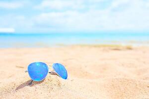 Sunglasses on the beach with ocean and sky on background photo