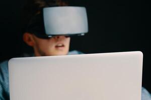 A young person in a VR headset with a laptop, symbolizing advanced technology and immersive digital experiences photo