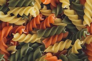 Colorful food background made with natural multicoloured fusilli. Minimal pasta concept. Creative food pattern backdrop. Pasta aesthetic. Flat lay style. Top view banner. photo