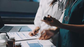 Two doctors are working on a laptop and tablet video