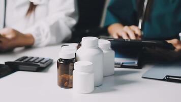 Two doctors sitting at a table with bottles and pills video