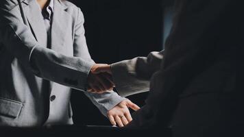 Two business people shaking hands in front of a computer video