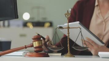 Lawyer working at desk with scales of justice and tablet video