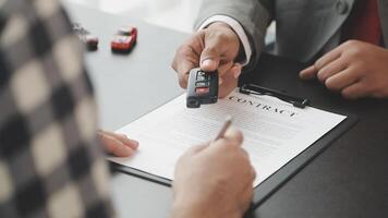A man holding a car key in front of a contract video