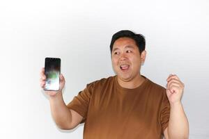 Excited Man Showing Smartphone and making yes gesture with a clenched left hand photo