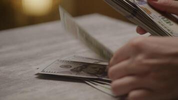 Hands counting stack of hundred-dollar bills on table video