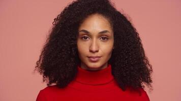 Confident woman in red turtleneck looking at camera on pink background video