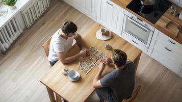 Two men playing a board game at a kitchen table photo