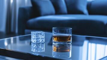 A glass of whiskey and ice cube on a table photo