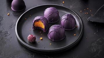 Purple chocolate truffles on a black plate photo
