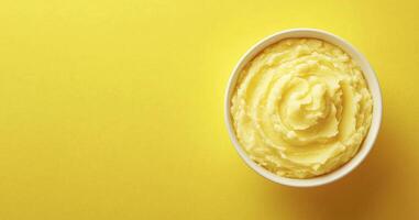 Creamy mashed potato in bowl isolated on yellow background with copy space photo