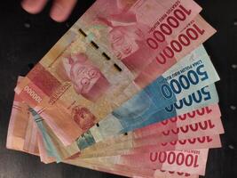 A close up view of Indonesia rupiah banknotes in various denominations, spread out against a dark black background photo