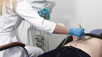 Confident doctor sitting in front of the screen and touching the stomach of the patient with ultrasound scanner video