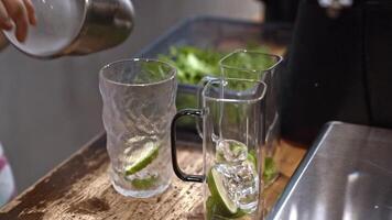 Bartender crafting lime drink, pouring ice, mixing fresh ingredients, capturing summer vibes, refreshing citrus cocktail, cold beverage preparation, glass filling, hydration focus, bar atmosphere. video
