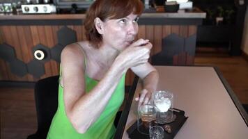 Woman enjoying ice cream dessert with espresso, savoring creamy indulgence at cafe table, stylish interior creating relaxed atmosphere, highlighting casual dining and moments of pure enjoyment. video