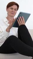 Woman Using Tablet at Home Sitting on Couch, Smiling and Relaxing, Concept of Digital Lifestyle, Technology, and Comfort in Cozy Interior, Focus on Modern Casual Interaction with Smart Device video