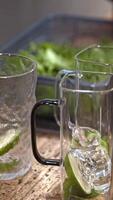 Refreshing lime cocktail making, bartender adding ice and fresh ingredients, summer drink preparation, cold citrus beverage, hydration, mixing process, vibrant bar scene, glass filled with flavor. video