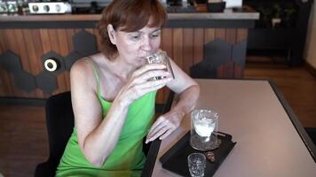 Savoring refreshing coffee in modern cafe, woman enjoying peaceful moment with drink, cozy atmosphere reflecting relaxation, indulgence, and urban lifestyle ambiance. video