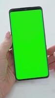 mão segurando Smartphone com verde croma chave tela, rolagem dedo movimento em mostrar, vertical posição, fechar-se interação e brincar conceito. video