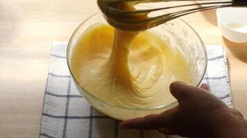 Hand Mixing Smooth Cake Batter with Whisk in Glass Bowl Baking Process on Wooden Kitchen Counter with Checkered Cloth Preparing Homemade Dessert with Eggs Flout and Sugar video