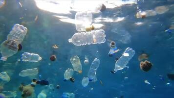 Underwater view of numerous plastic bottles and debris polluting the ocean environment, blue hue video