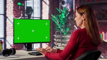 Confident woman solves freelancing tasks at copy space desktop, browsing the internet pages at her home office. Mature focused person self employed doing her job remotely. Camera A. video