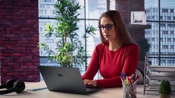 Mature person overseeing business schedule and planning activities at desk, working on time management with digital tools. Female freelancer utilizing the pc and multitasking. Camera B. video