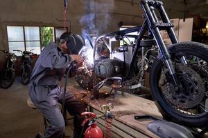 Faceless mechanic working with welding machine while repairing m photo