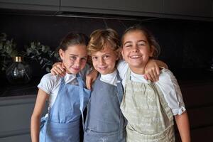 Delightful kids in aprons in dark kitchen photo