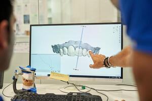 Unrecognizable prosthodontists examining denture on computer photo