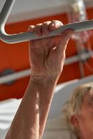 Crop anonymous elderly woman holding handle while lying on medic photo