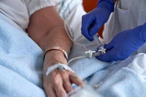 Crop nurse injecting patient with drug intravenously photo