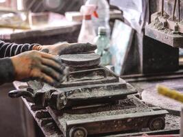 Crop craftsman pouring dry clay into mold while creating tile photo