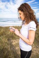 Young woman with sportswear looking her smartphone photo