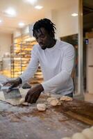Black baker cutting dough with scapula photo
