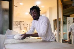 Black baker with a dough in his hands photo