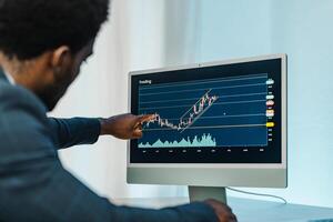 Black man analyzing financial diagrams on binary option photo