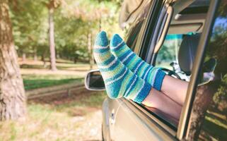 Female legs with socks resting over open window car photo