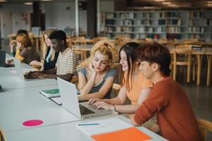 Multiracial young students using netbooks in library photo
