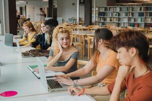 Focused multiracial classmates using netbook in library while doing research photo